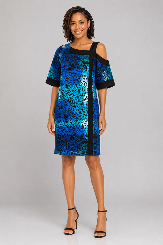 A woman modeling a short-sleeve cold-shoulder dress with a blue and black abstract pattern, standing against a light gray studio background.