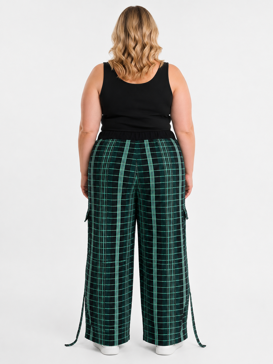 A woman shown from the back wearing dark green wide-leg plaid pants with a black tank top, against a light gray studio background.