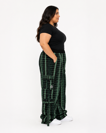 A woman in a black t-shirt and green plaid cargo pants with white sneakers, shown in a side profile against a plain white studio background.