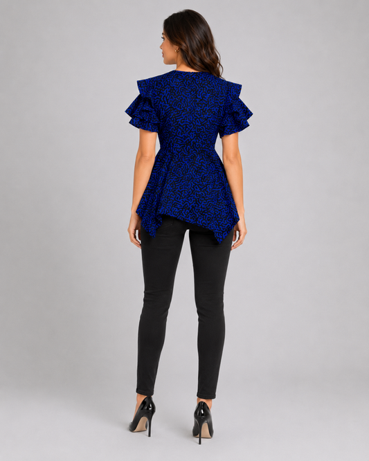 A woman shown from the back wearing a royal blue lace ruffled short-sleeve top, black skinny pants, and black high heels against a light gray studio background.